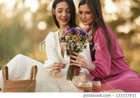 With bouquet of flowers. Lesbian couple is together on the picnic in nature 133337631