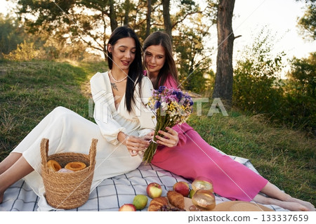 Fruits, flowers and glasses of drink. Lesbian couple is together on the picnic in nature Fruits, flowers and glasses of drink. Lesbian couple is together on the picnic in nature 133337659