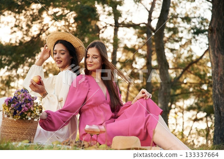 Fresh fruits and flowers. Lesbian couple is together on the picnic in nature Fresh fruits and flowers. Lesbian couple is together on the picnic in nature 133337664