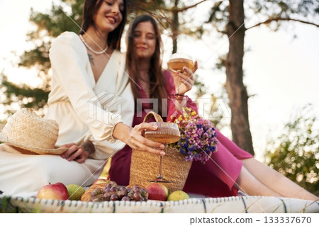 Sitting, bunch of fruits and flowers bouquet. Lesbian couple is together on the picnic in nature Sitting, bunch of fruits and flowers bouquet. Lesbian couple is together on the picnic in nature 133337670