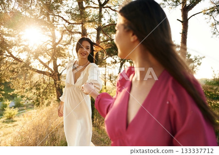 Side view, having a walk. Lovely lesbian couple are together outdoors in nature Side view, having a walk. Lovely lesbian couple are together outdoors in nature 133337712