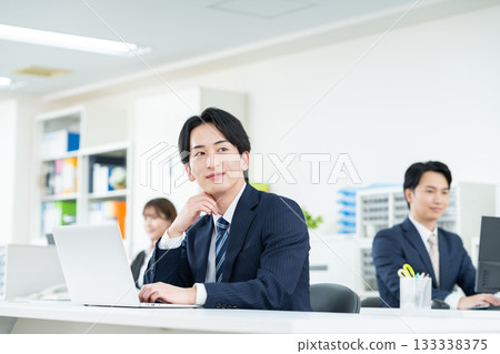 工作在辦公室的一個年輕商人 工作在辦公室的一個年輕商人 133338375