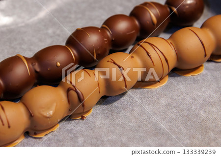 Closeup of two milk and dark chocolate coated grape dessert skewers at a festive christmas or advent market. Closeup of two milk and dark chocolate coated grape dessert skewers at a festive christmas or advent market. 133339239