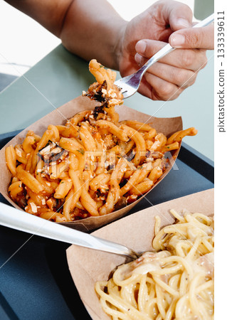 man about to eat casarecce alla norma outdoors 133339611