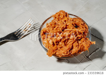 a glass bowl filled with rich tender pulled pork 133339618