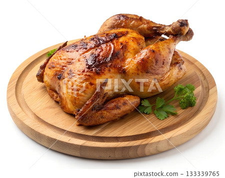 Whole roasted chicken with crispy golden brown skin and parsley garnish on a wooden board 133339765