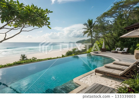 Luxury infinity pool overlooks pristine tropical beach with turquoise ocean waves and lush green vegetation Luxury infinity pool overlooks pristine tropical beach with turquoise ocean waves and lush green vegetation 133339803