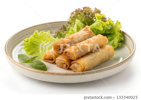 Crispy golden spring rolls served with fresh green lettuce and a basil leaf on a plate 133340025