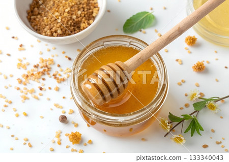 Golden honey in a glass jar with a wooden dipper bee pollen and small flowers Golden honey in a glass jar with a wooden dipper bee pollen and small flowers 133340043