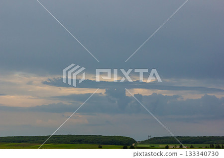 Cloud formation at dusk over rolling hills with hints of blue sky and layered clouds on a tranquil evening 133340730