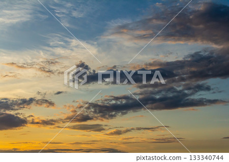 Stunning sunset over the horizon with vibrant colors and dynamic cloud formations at twilight in a tranquil outdoor setting Stunning sunset over the horizon with vibrant colors and dynamic cloud formations at twilight in a tranquil outdoor setting 133340744