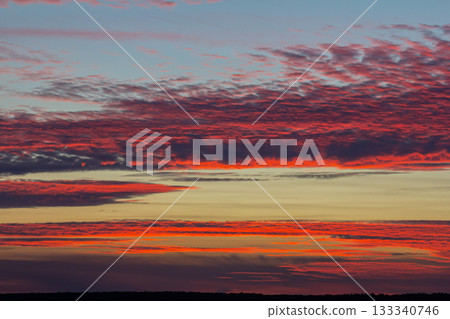 Colorful sunrise over horizon during early morning in serene landscape with scattered clouds creating a dynamic sky Colorful sunrise over horizon during early morning in serene landscape with scattered clouds creating a dynamic sky 133340746