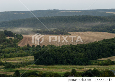 Tractor preparing a harvested field in a scenic rural landscape during late afternoon in a tranquil countryside 133340812
