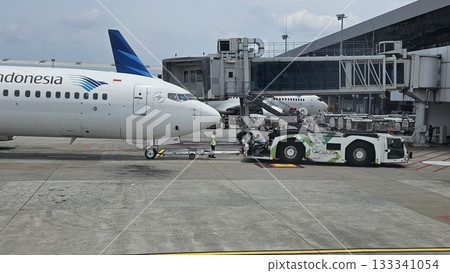This white passenger jet, bearing the "SKYTEAM" logo, is being pushed back from the airport gate. This white passenger jet, bearing the "SKYTEAM" logo, is being pushed back from the airport gate. 133341054
