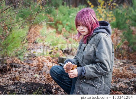 Girl with pink hair finding mushroom in forest 133341294