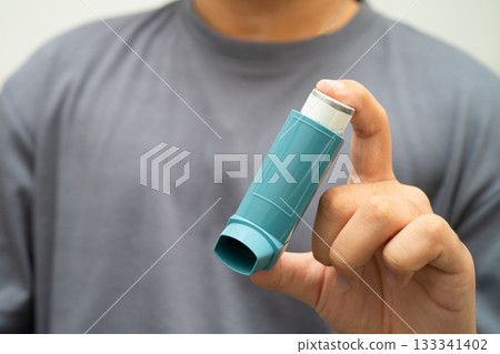Asthma and chronic obstructive pulmonary disease COPD, Asian young man using metered dose inhaler MDI. Asthma and chronic obstructive pulmonary disease COPD, Asian young man using metered dose inhaler MDI. 133341402