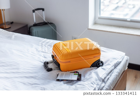 Orange suitcase on hotel bed welcoming travelers arrival 133341411
