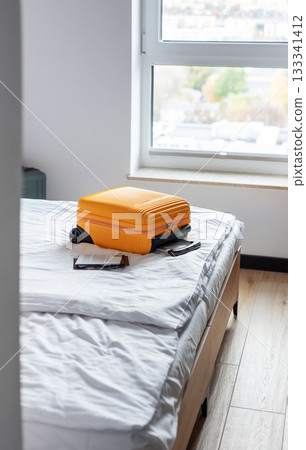 Orange luggage suitcase sitting on hotel bed 133341412