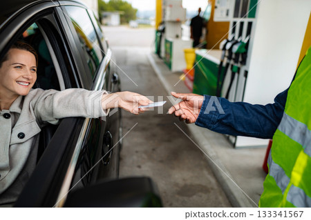 Woman paying for gas with credit card at service station Woman paying for gas with credit card at service station 133341567