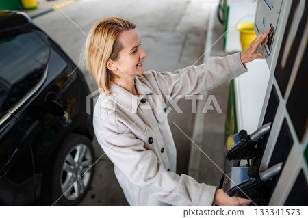 Woman selecting fuel type at gas station Woman selecting fuel type at gas station 133341573