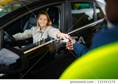 Woman paying with credit card at drive-thru service window Woman paying with credit card at drive-thru service window 133341574