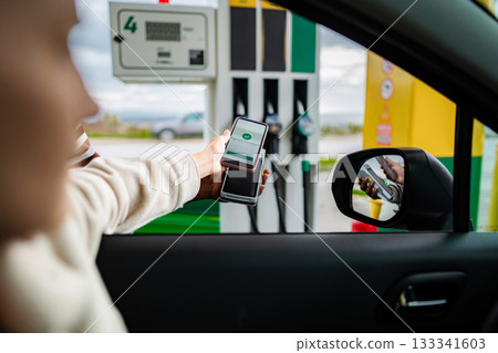 Woman paying for gas using smartphone contactless payment 133341603