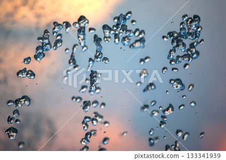 flying drops of water fountain close-up on the background of the sky 133341939