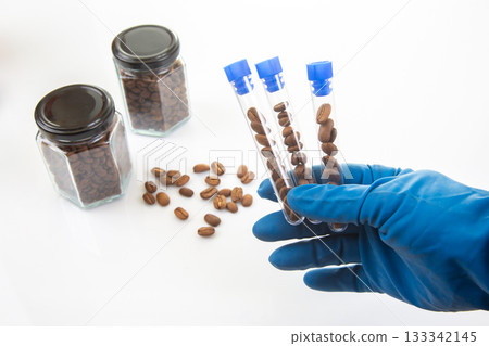 Coffee beans are meticulously studied in a laboratory setting, with test tubes 133342145