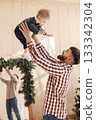 Happy father throw in the air his cute little son. Bearded man and little boy wearing plaid shirts. Father with son standing in room with Christmas atmosphere. 133342304