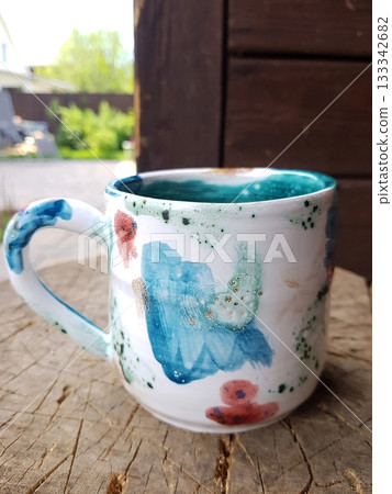 Hand-Painted Ceramic Mug on Tree Stump Outdoors Hand-Painted Ceramic Mug on Tree Stump Outdoors 133342682
