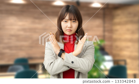 A woman with a troubled expression making a cross pose with her hands 133342843