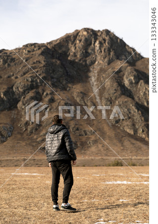 Man Walking Across Vast Mountain Field in Winter Man Walking Across Vast Mountain Field in Winter 133343046