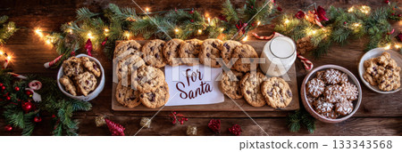 Editorial panoramic shot of a long wooden table adorned with cookies, milk, and festive decorations for Santa on Christmas Eve 133343568