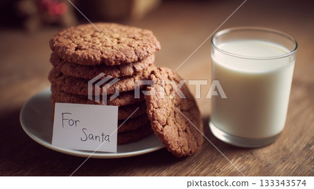 Gingerbread cookies stacked neatly beside a glass of milk with a handwritten card for Santa, creating a warm festive Christmas Eve atmosphere 133343574