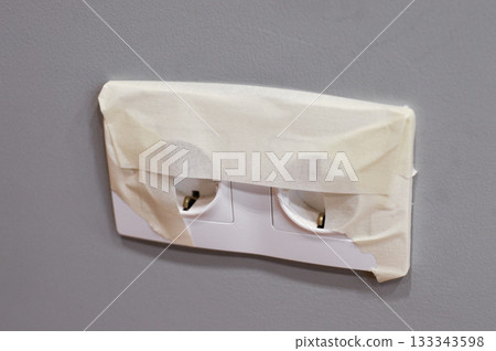 The outlet with sticky tape to protect it from paint during repairs. The outlet with sticky tape to protect it from paint during repairs. 133343598