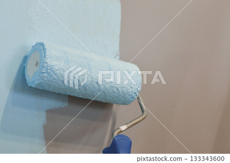 A construction professional is applying a fresh coat of bright white paint to an interior wall using a roller brush, as part of an apartment renovation project. A construction professional is applying a fresh coat of bright white paint to an interior wall using a roller brush, as part of an apartment renovation project. 133343600