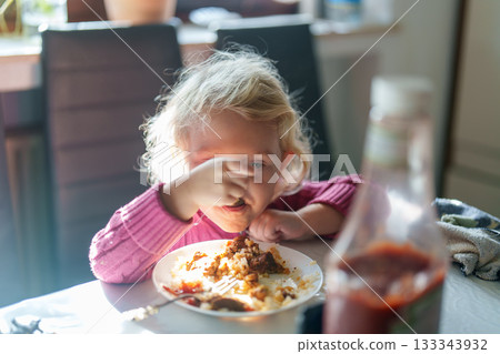 little girl eating pizza in the kitchen 133343932