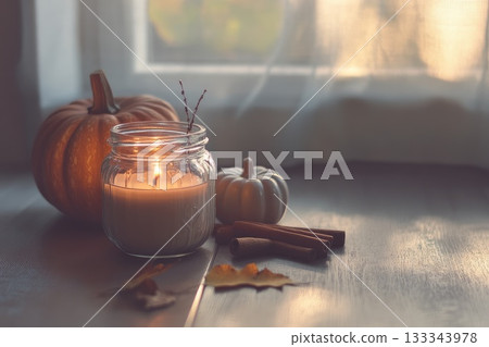 A lovely candle in a jar sits beside colorful pumpkins and cinnamon. AI-generated content. 133343978