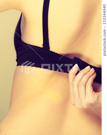 Woman dressing up her bra rear view 133344040
