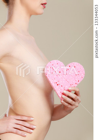 Naked woman holding pink heart sponge in hands. Naked woman holding pink heart sponge in hands. 133344053