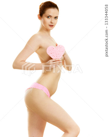 Sensual naked woman with beautiful figure perfect skin holding pink heart shaped bath sponge in hands. 133344058