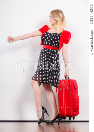 woman with red suitcase hitchhiking 133344296