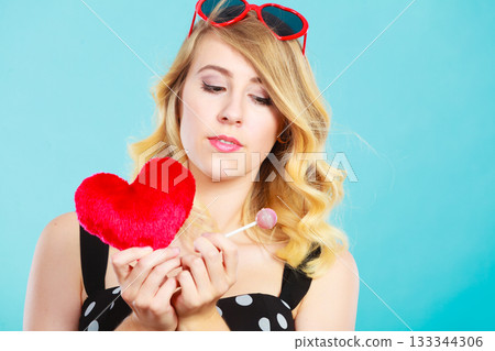Woman holds red heart love symbol and lollipop candy 133344306