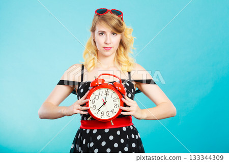 Smiling girl with alarm clock on blue. 133344309
