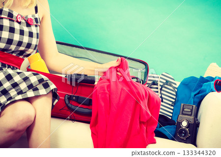 Woman choosing things to pack into suitcase Woman choosing things to pack into suitcase 133344320