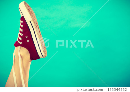 Person tying red sneaker with foot up 133344332