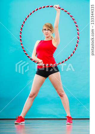 Fit woman with hula hoop doing exercise 133344335