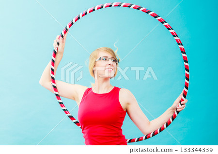 Fit woman with hula hoop doing exercise 133344339