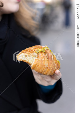 Hand Holding Fresh Pistachio Croissant Outdoors Hand Holding Fresh Pistachio Croissant Outdoors 133344541