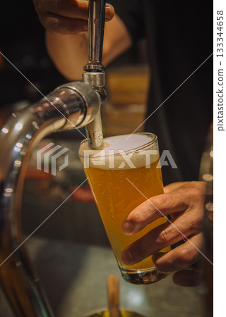 一隻手正在從龍頭倒出生啤酒。 133344658